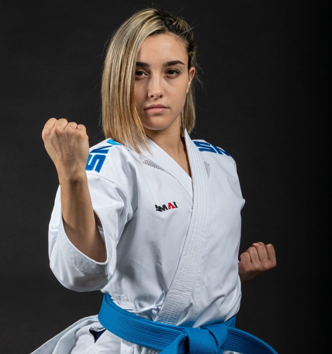 Karateka in Kaminari X Gi mit blauer Gürtelschärfe, zeigt eine Kampfhaltung.