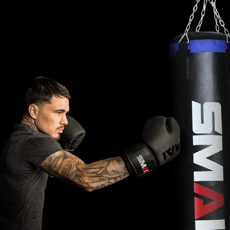 Boxer mit SMAI Boxhandschuhen schlägt einen SMAI Boxsack in einer dunklen Umgebung.