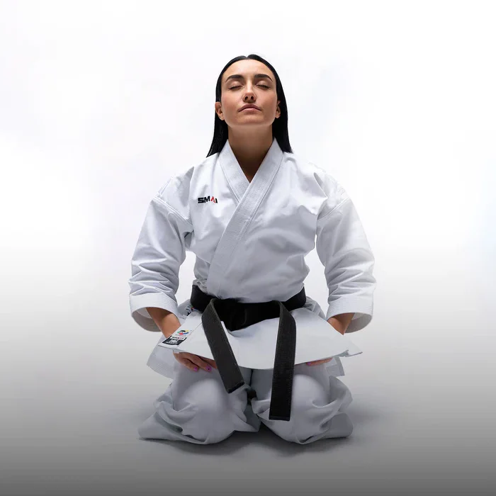 Eine Person in Karate-Uniform von SMAI mit schwarzem Gürtel, in der Kniestellung.
